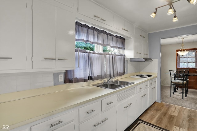 kitchen with light wood-style floors, a sink, light countertops, white cabinets, and white cooktop