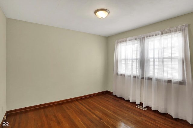 empty room with baseboards and dark wood finished floors