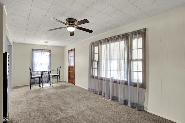 carpeted dining space featuring ceiling fan and baseboards