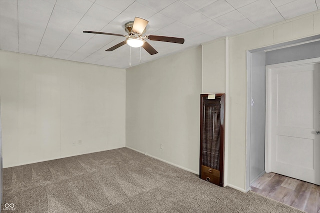 spare room with a heating unit, ceiling fan, and carpet