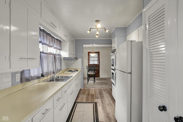 kitchen with freestanding refrigerator, wood finished floors, white cabinets, ornamental molding, and light countertops