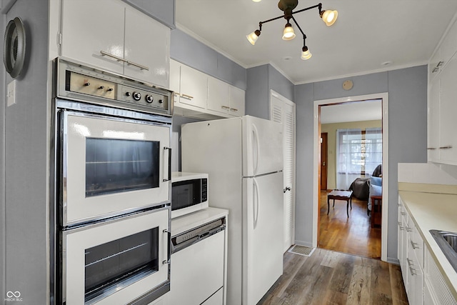 kitchen with dark wood finished floors, white appliances, light countertops, crown molding, and white cabinets
