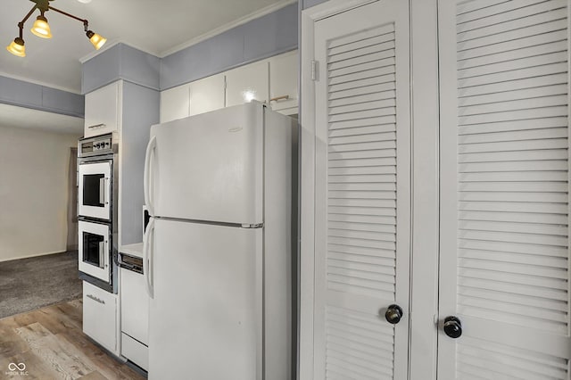kitchen with white appliances, white cabinets, ornamental molding, and light wood-type flooring