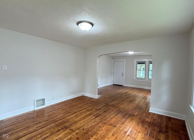1032 Groff Ave, Indianapolis, IN 46222 - unfurnished room with arched walkways, hardwood / wood-style floors, a textured ceiling, and baseboards