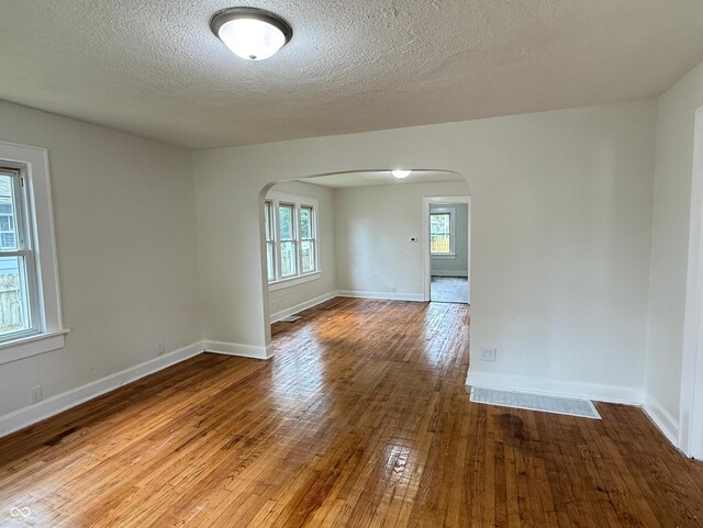 1032 Groff Ave, Indianapolis, IN 46222 - unfurnished room featuring arched walkways, hardwood / wood-style floors, a textured ceiling, and baseboards