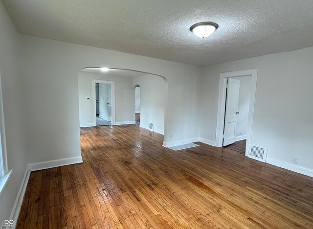 1032 Groff Ave, Indianapolis, IN 46222 - spare room featuring arched walkways, hardwood / wood-style flooring, a textured ceiling, and baseboards