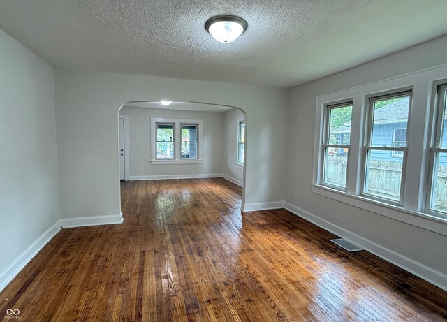 1032 Groff Ave, Indianapolis, IN 46222 - unfurnished room with arched walkways, a textured ceiling, baseboards, and dark wood-type flooring