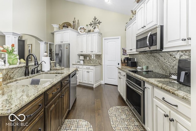 kitchen featuring stainless steel appliances, white cabinets, ornate columns, and a sink
