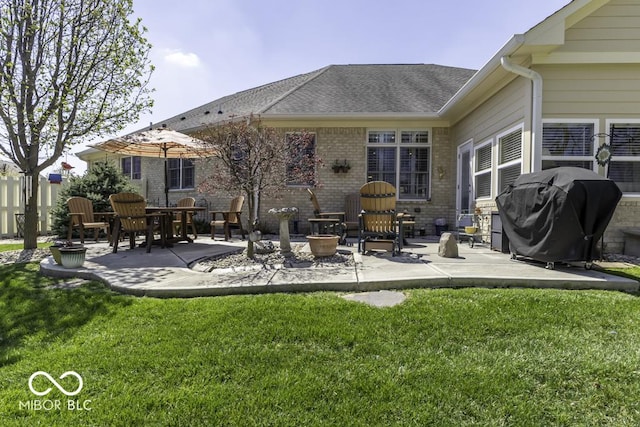 rear view of property featuring a yard, brick siding, and a patio