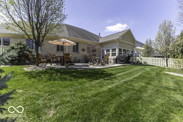 rear view of property with brick siding, a yard, a patio, and fence