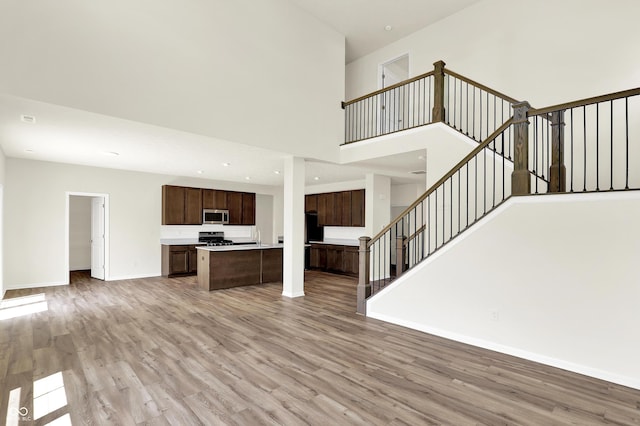 3727 Thomas Jefferson Ct, Westfield, IN 46074 - unfurnished living room featuring light wood-style flooring, stairway, baseboards, and a towering ceiling