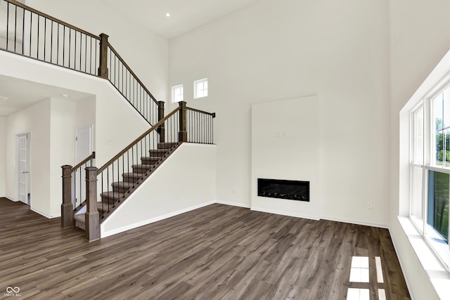 3727 Thomas Jefferson Ct, Westfield, IN 46074 - unfurnished living room featuring a towering ceiling, wood finished floors, a fireplace, baseboards, and stairs