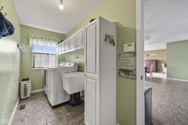 washroom featuring independent washer and dryer, a textured ceiling, dark tile patterned floors, and visible vents
