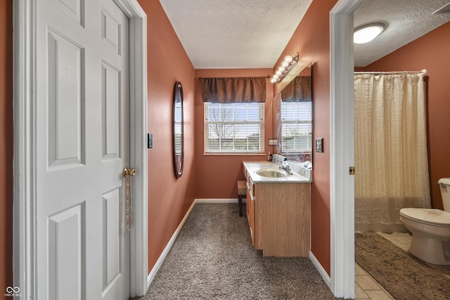 bathroom featuring vanity, a textured ceiling, baseboards, and toilet