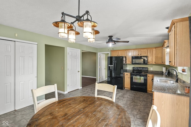 kitchen with baseboards, black appliances, ceiling fan with notable chandelier, a sink, and dark tile patterned flooring