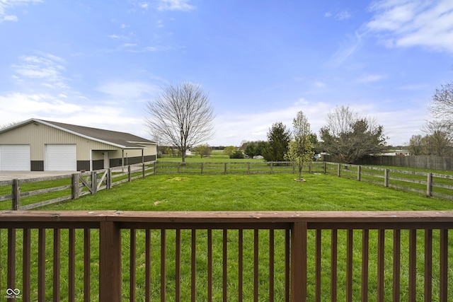 view of yard with a rural view, a garage, an exterior structure, and an outdoor structure