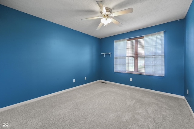 empty room with a textured ceiling, baseboards, a ceiling fan, and carpet
