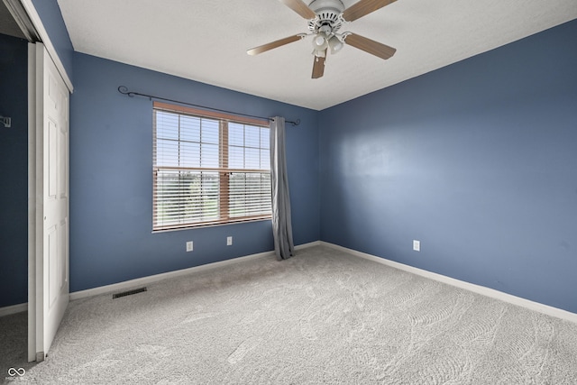 carpeted spare room featuring visible vents, ceiling fan, and baseboards