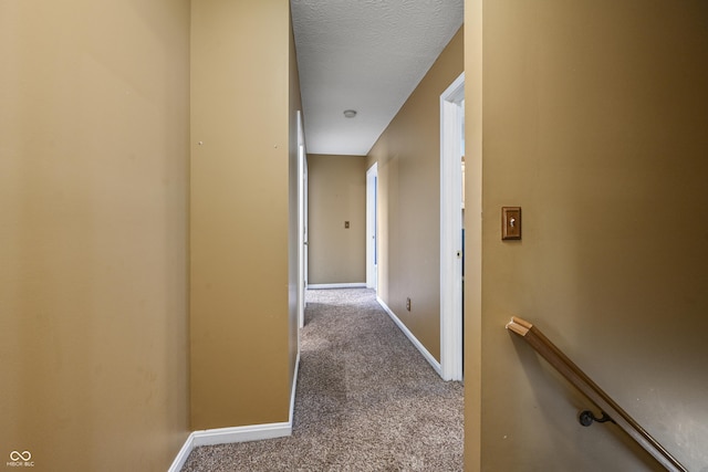 hall featuring baseboards, an upstairs landing, and carpet