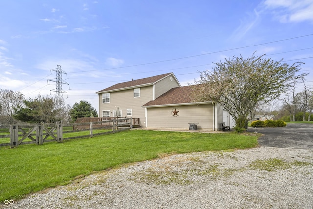 rear view of house with a gate, a lawn, a deck, fence, and a shingled roof