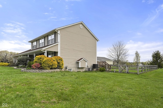 view of side of property featuring fence, cooling unit, and a lawn