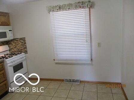 kitchen with visible vents, baseboards, white appliances, and light tile patterned floors