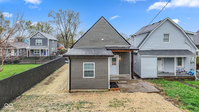 back of property featuring fence, a shingled roof, and a lawn