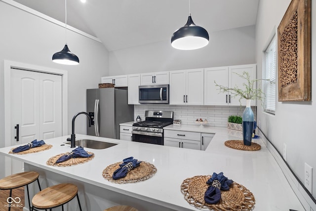 kitchen with a sink, stainless steel appliances, decorative backsplash, a breakfast bar area, and lofted ceiling