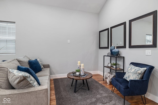 living area featuring baseboards, vaulted ceiling, and wood finished floors