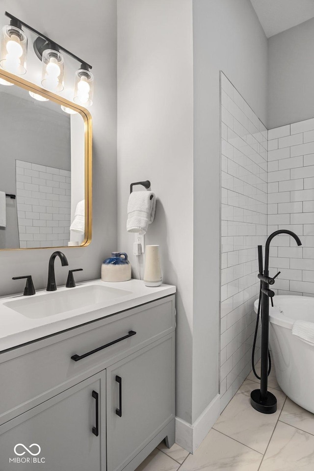 full bathroom with a freestanding tub, vanity, and marble finish floor