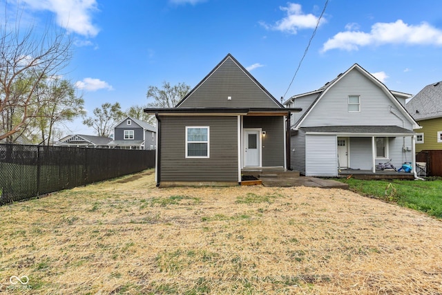 rear view of house with a yard and fence