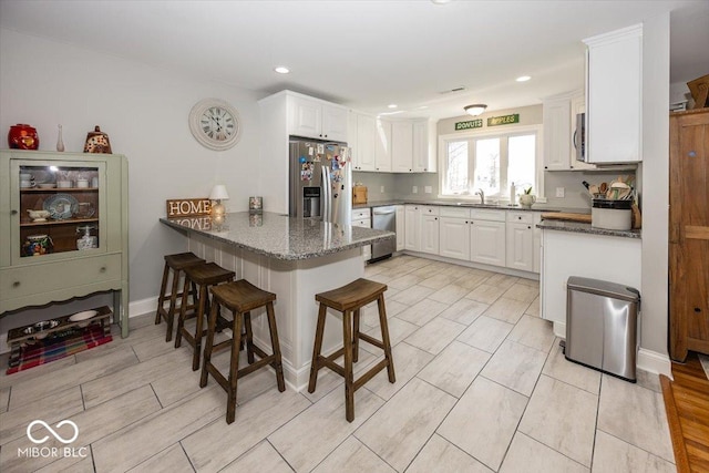 19702 Tomlinson Rd, Westfield, IN 46074 - kitchen with a peninsula, white cabinets, appliances with stainless steel finishes, a sink, and a breakfast bar area