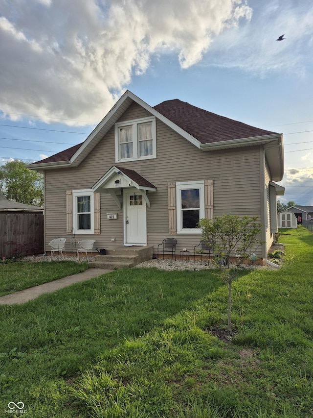 view of front of property with fence, a shingled roof, and a front lawn