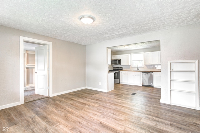 6189 Vigo Dr, Clayton, IN 46118 - unfurnished living room featuring light wood-type flooring, a textured wall, and a textured ceiling