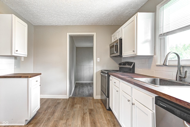 6189 Vigo Dr, Clayton, IN 46118 - kitchen with wood counters, stainless steel appliances, wood finished floors, white cabinetry, and a textured ceiling
