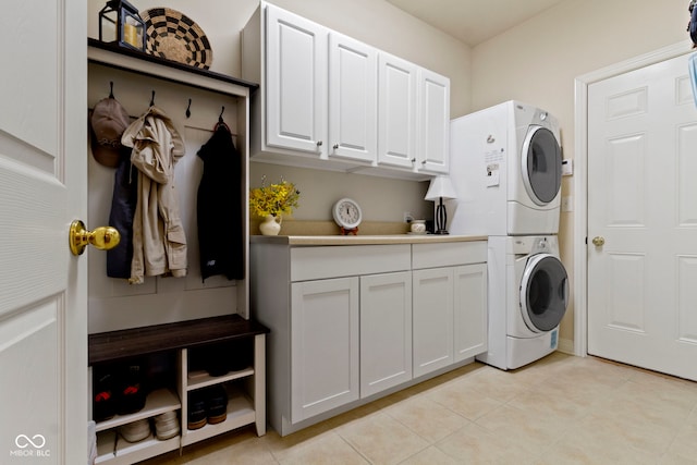 laundry area with cabinet space, stacked washer / drying machine, and light tile patterned floors