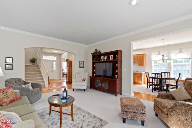 living room with arched walkways, ornamental molding, stairs, and a wealth of natural light