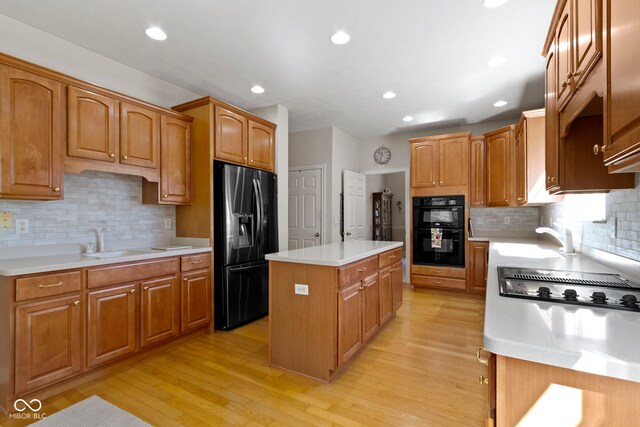 kitchen featuring decorative backsplash, a center island, a sink, and black appliances