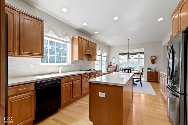 kitchen with black dishwasher, freestanding refrigerator, a center island, and light wood finished floors