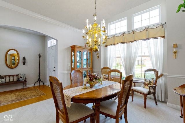 dining space featuring a chandelier, light wood-style floors, arched walkways, baseboards, and ornamental molding