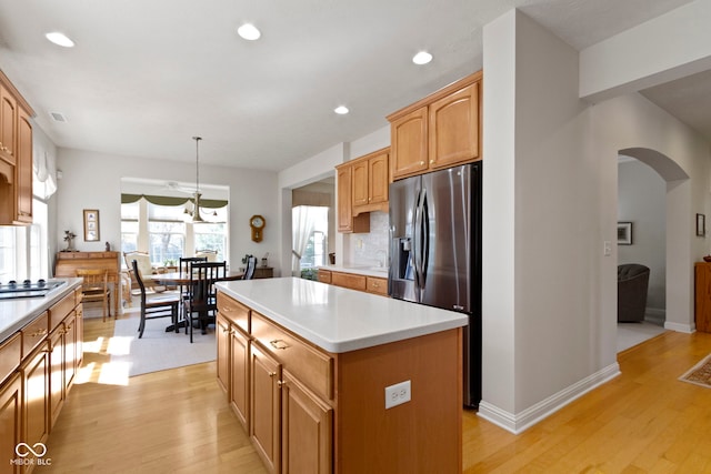 kitchen featuring a center island, arched walkways, appliances with stainless steel finishes, and light wood-style flooring