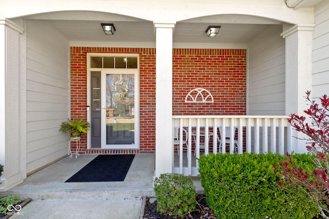entrance to property featuring brick siding and covered porch