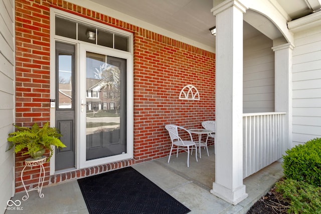 doorway to property with brick siding and covered porch