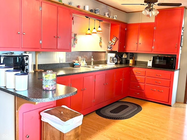 kitchen featuring black microwave, light wood finished floors, ceiling fan, and red cabinetry
