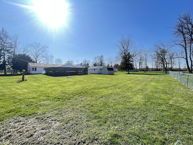view of yard with an outbuilding, fence, and a shed