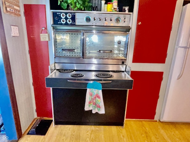 kitchen with freestanding refrigerator, oven, and wood finished floors