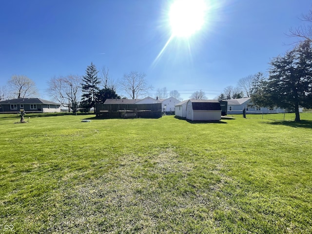 view of yard featuring an outbuilding, fence, and a storage shed