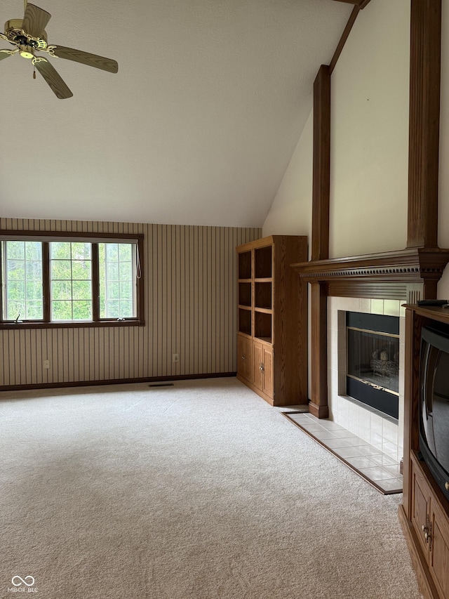 unfurnished living room with ceiling fan, light carpet, visible vents, a fireplace, and vaulted ceiling