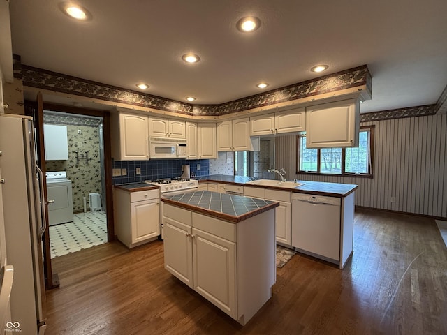 kitchen featuring washer / clothes dryer, a sink, wallpapered walls, white appliances, and dark wood-type flooring