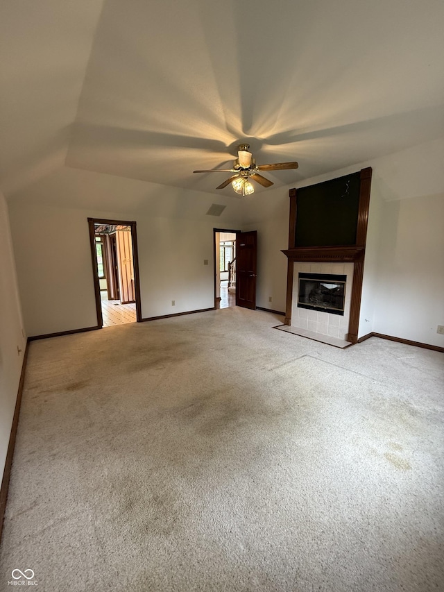 unfurnished living room featuring lofted ceiling, baseboards, ceiling fan, light colored carpet, and a tiled fireplace